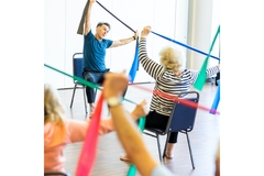 Older people working out with bands at a gym.